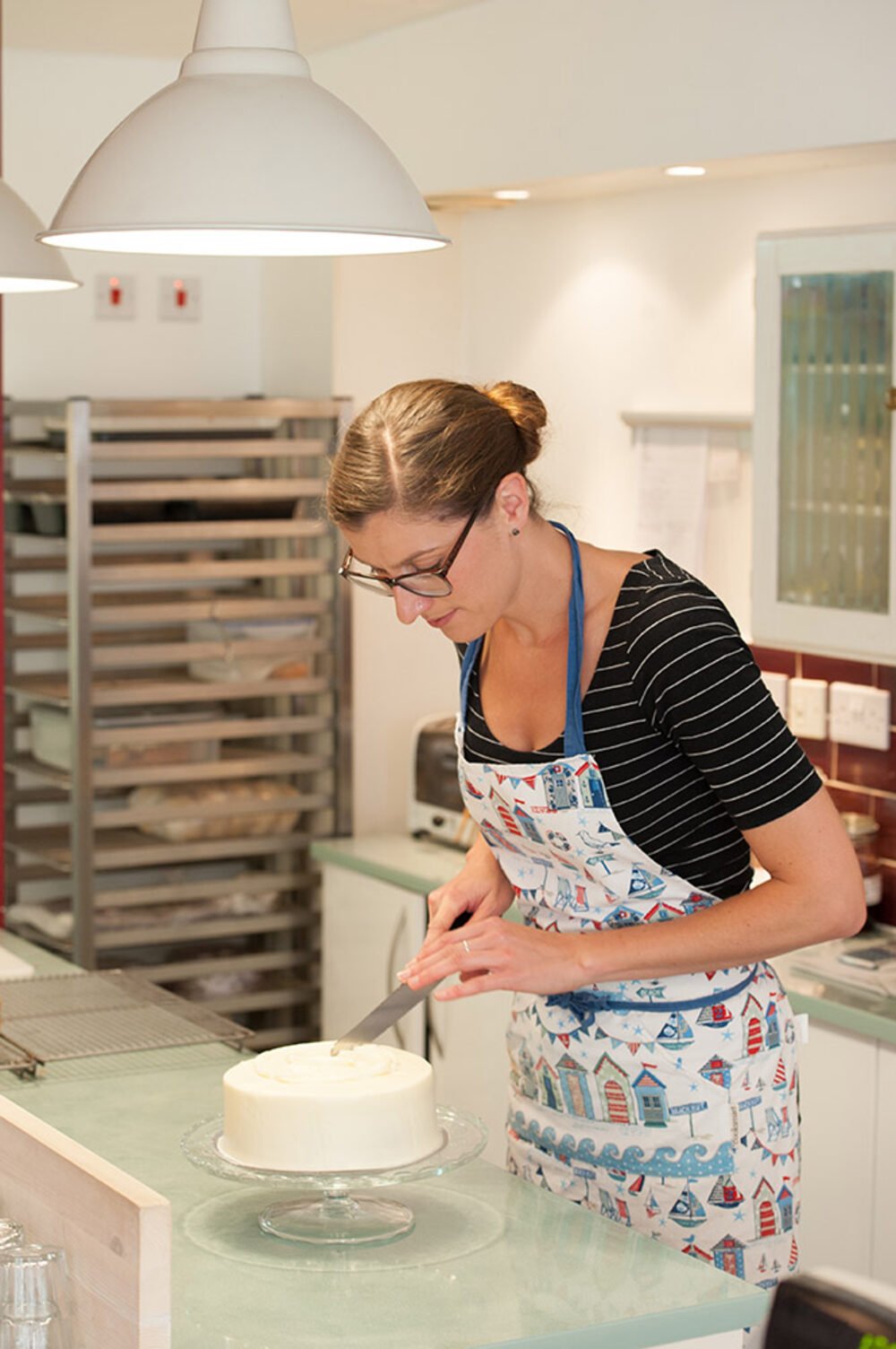 Cambridge cake-shop owner icing a cake in her kitchen, photographed by Jean-Luc Benazet.