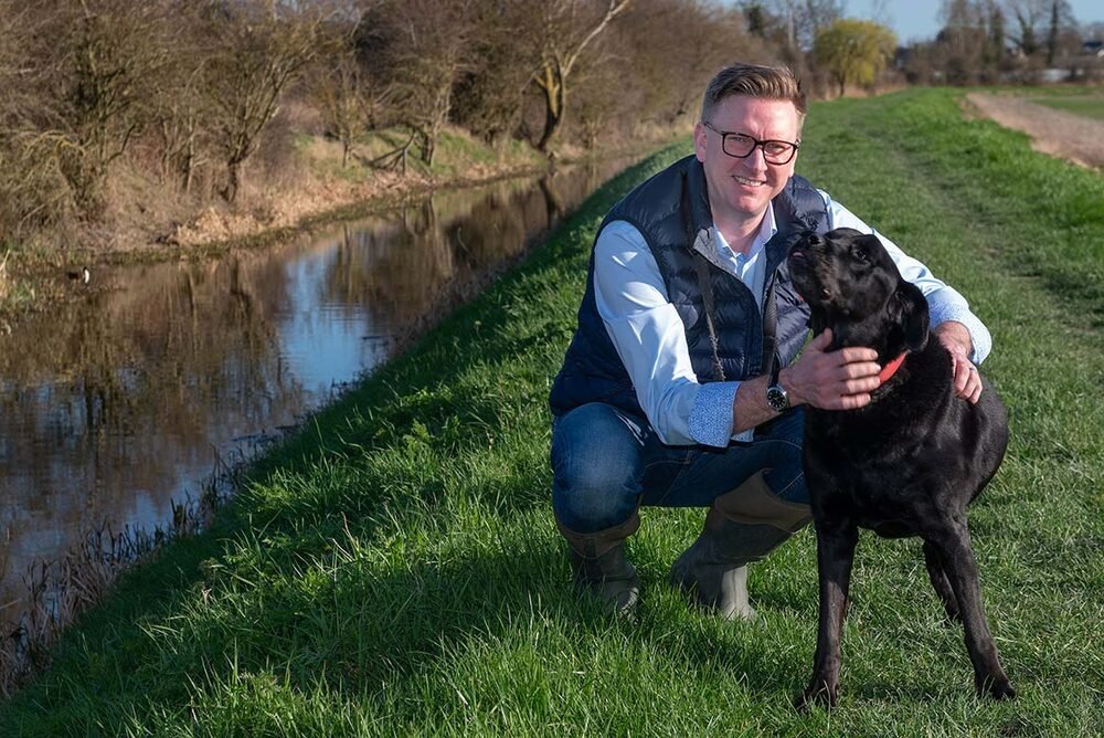 Personal brand portrait with a dog on a Cambridgeshire canal towpath.