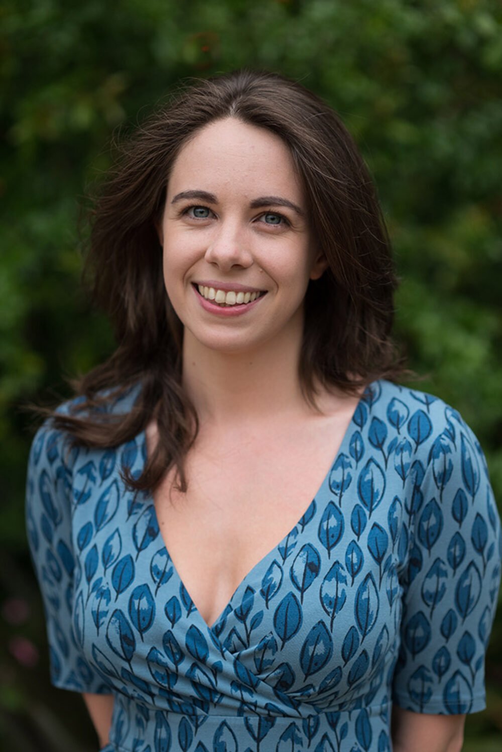 Personal brand portrait in natural light against a foliage backdrop.