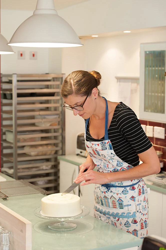 Person decorating a cake at a kitchen worktop
