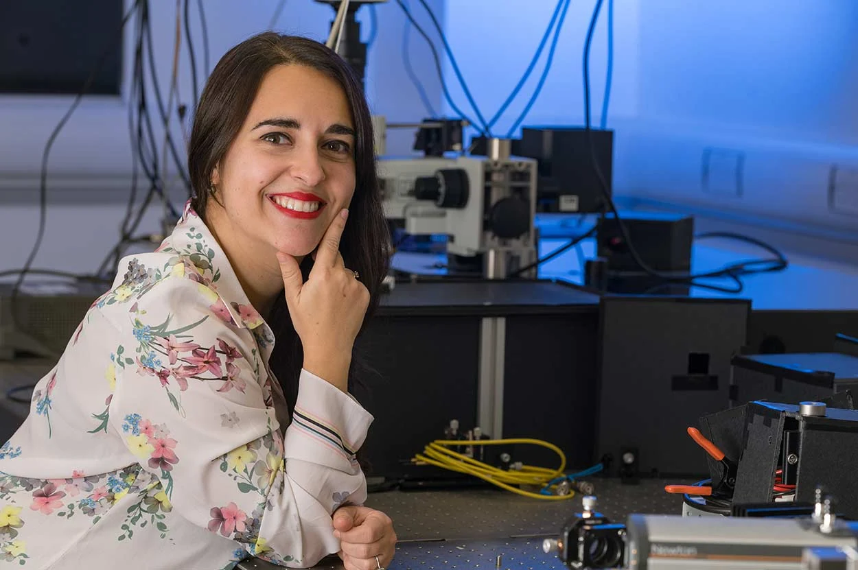 Woman smiling beside technical equipment in a workspace