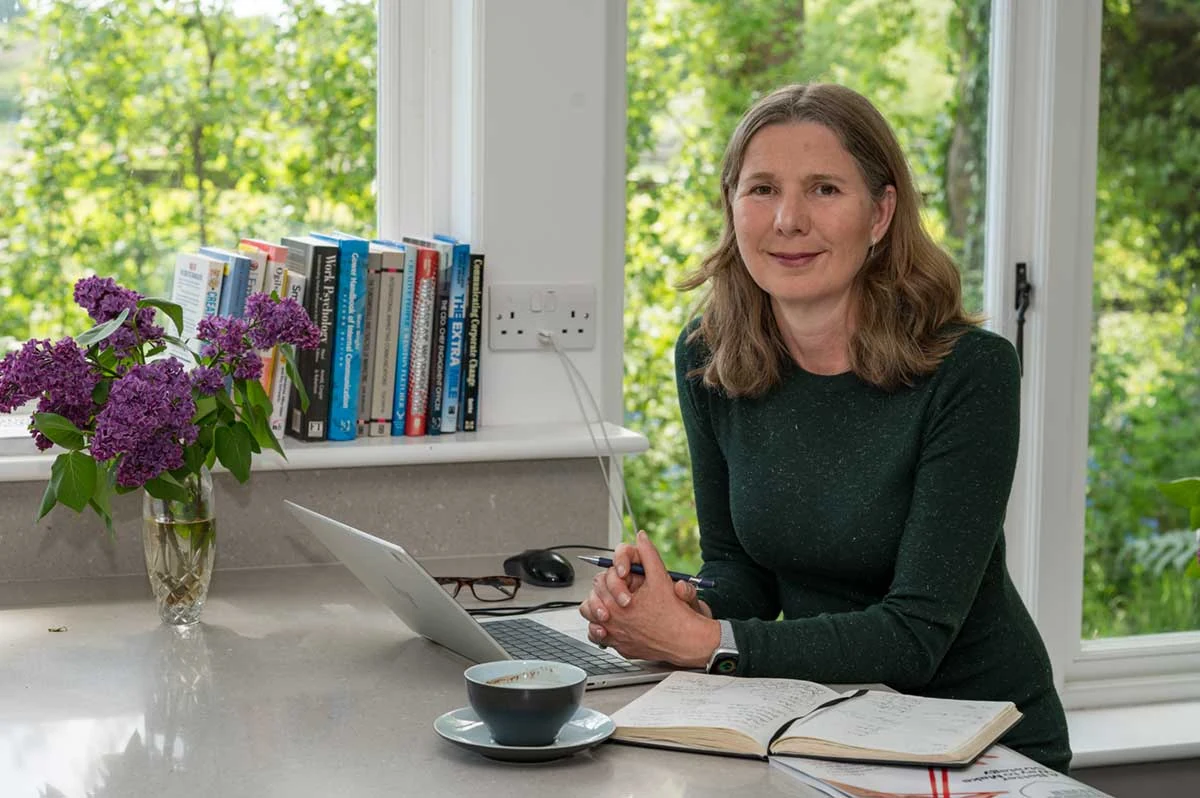A working portrait beside a laptop in a bright room