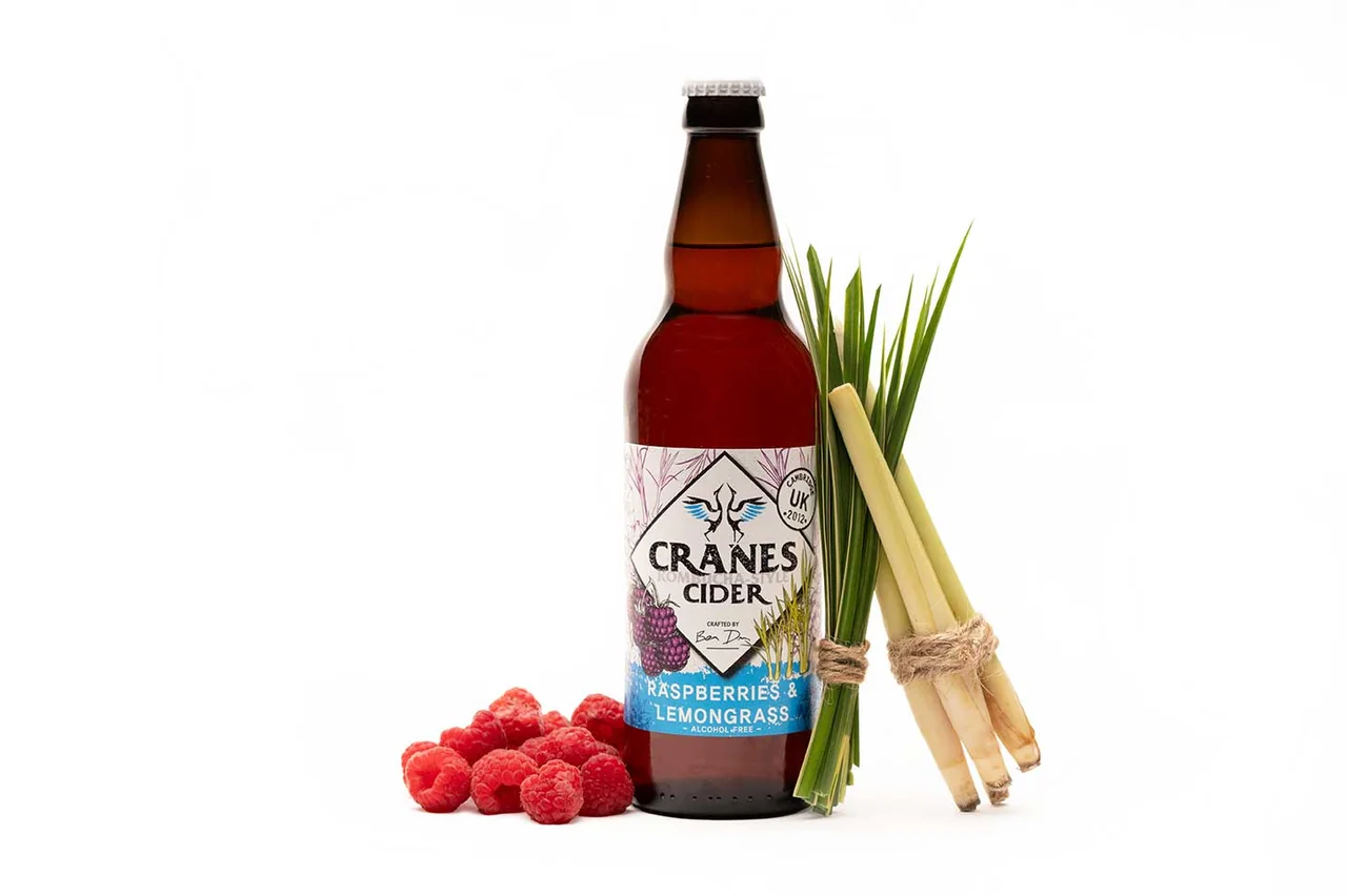 A bottle of Cranes cider with lemongrass and raspberries on a white background