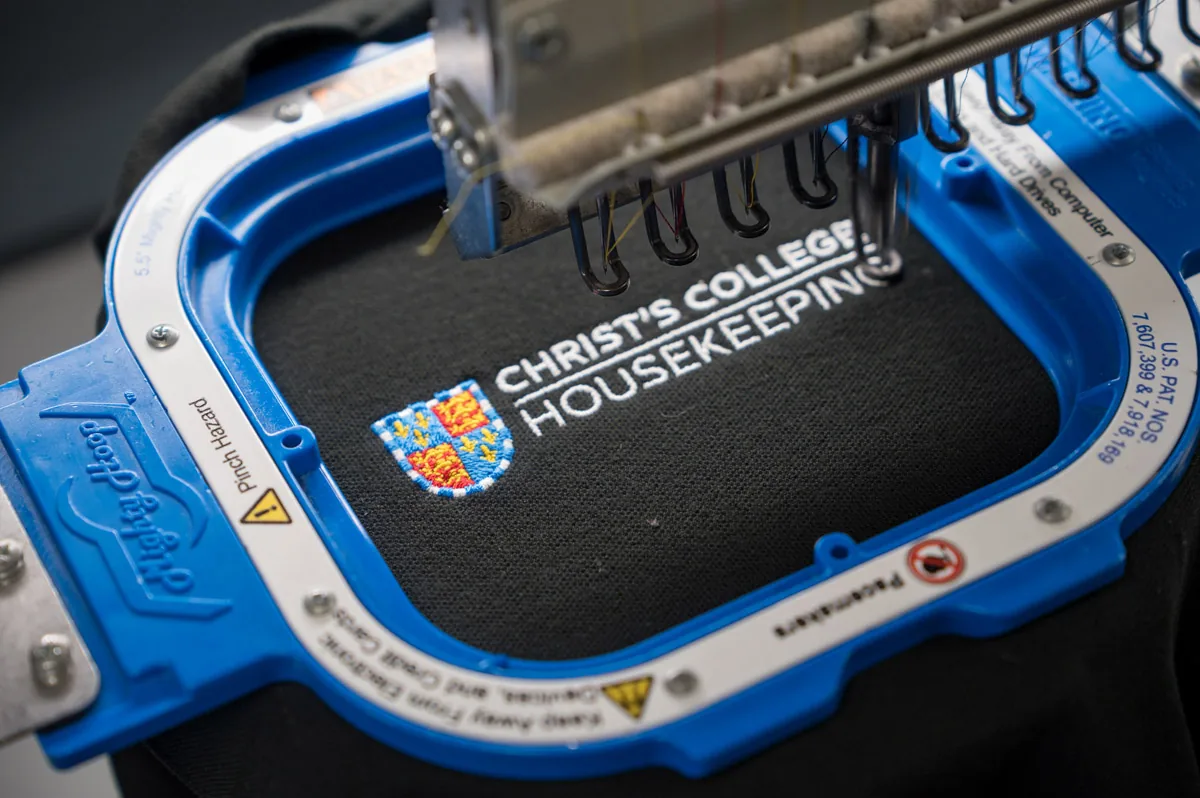 A Christ’s College housekeeping logo being embroidered on a machine hoop
