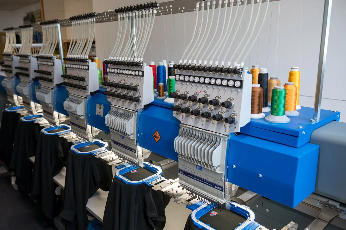 A row of Sigma industrial embroidery machines with coloured threads