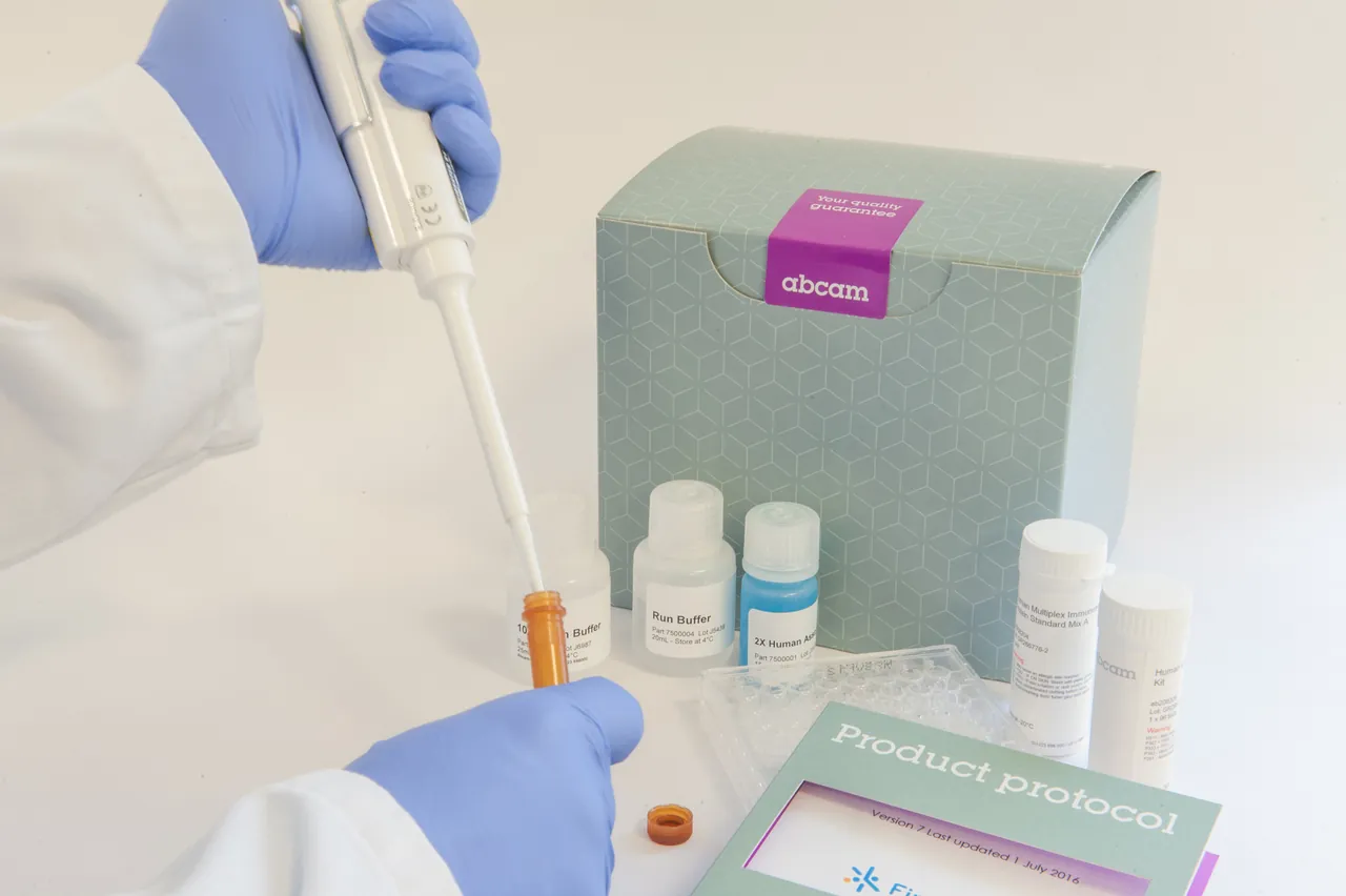 A gloved hand pipetting a sample next to a boxed Abcam product kit