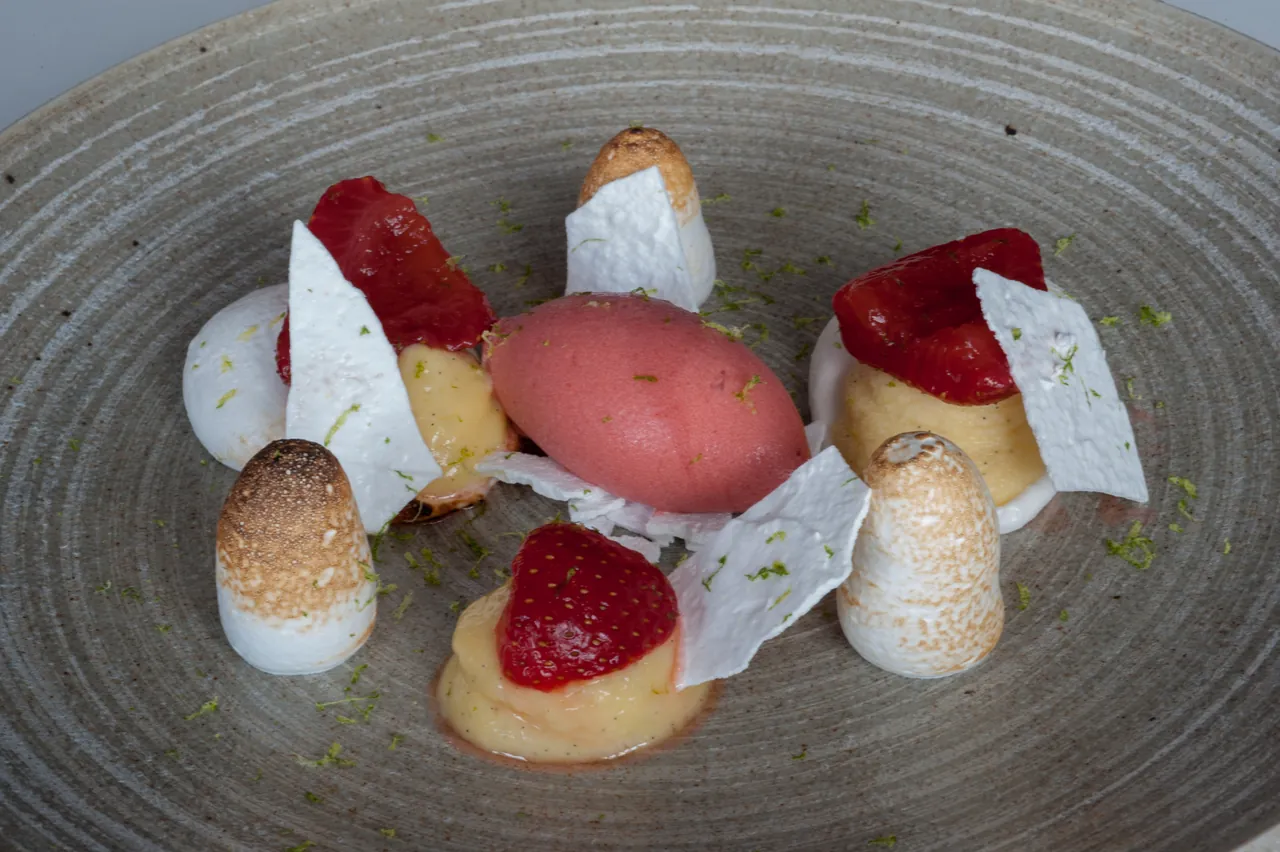 A strawberry dessert with meringues on a grey stone plate