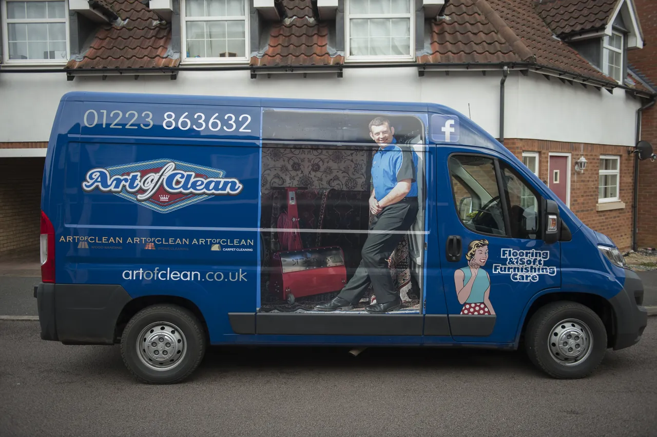 A liveried cleaning company van parked on a residential street