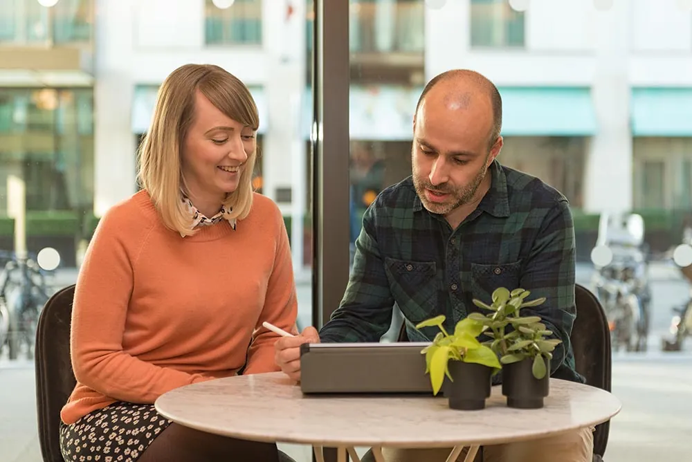 Two colleagues working together at a café table by a window