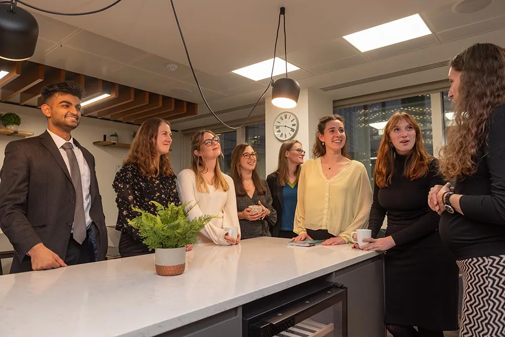 A team standing and talking around an office kitchen island