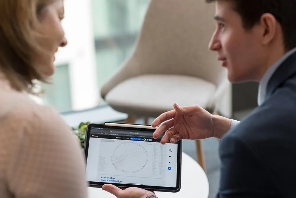 A man showing a colleague a chart on a tablet