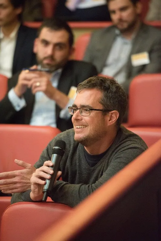 A delegate in a theatre seat asking a question into a handheld microphone