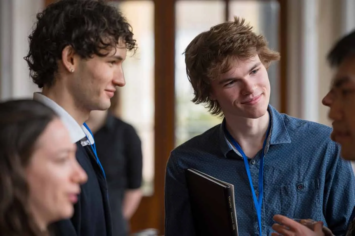 Two young delegates with lanyards smiling in conversation at a conference