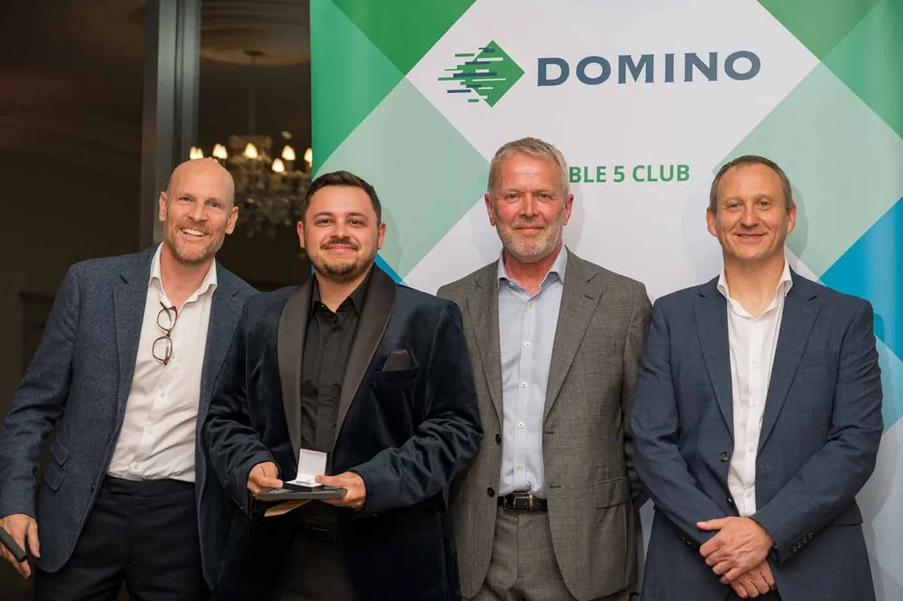 Four men at a Domino awards evening, one holding his award