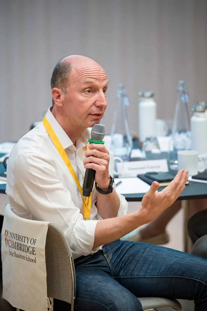 A participant speaking into a microphone during a discussion at Cambridge Judge Business School