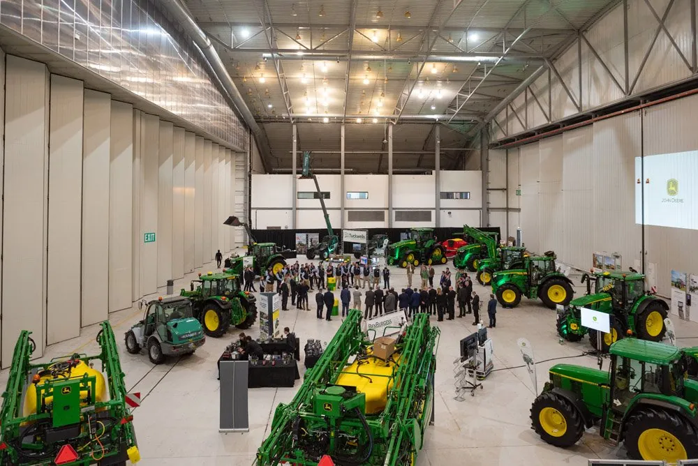 A product launch in a large hall filled with green tractors and guests