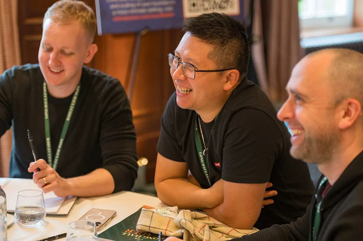Three delegates laughing together at a workshop table