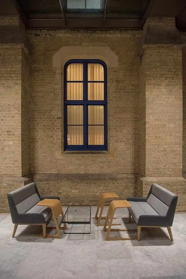 Two armchairs beneath an arched window in a brick-walled space