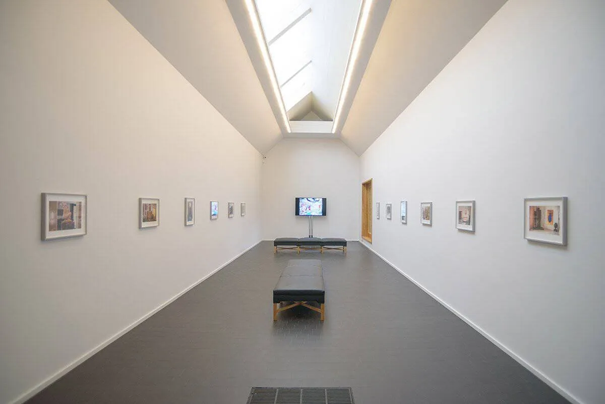 A long, narrow gallery with framed works and rooflights
