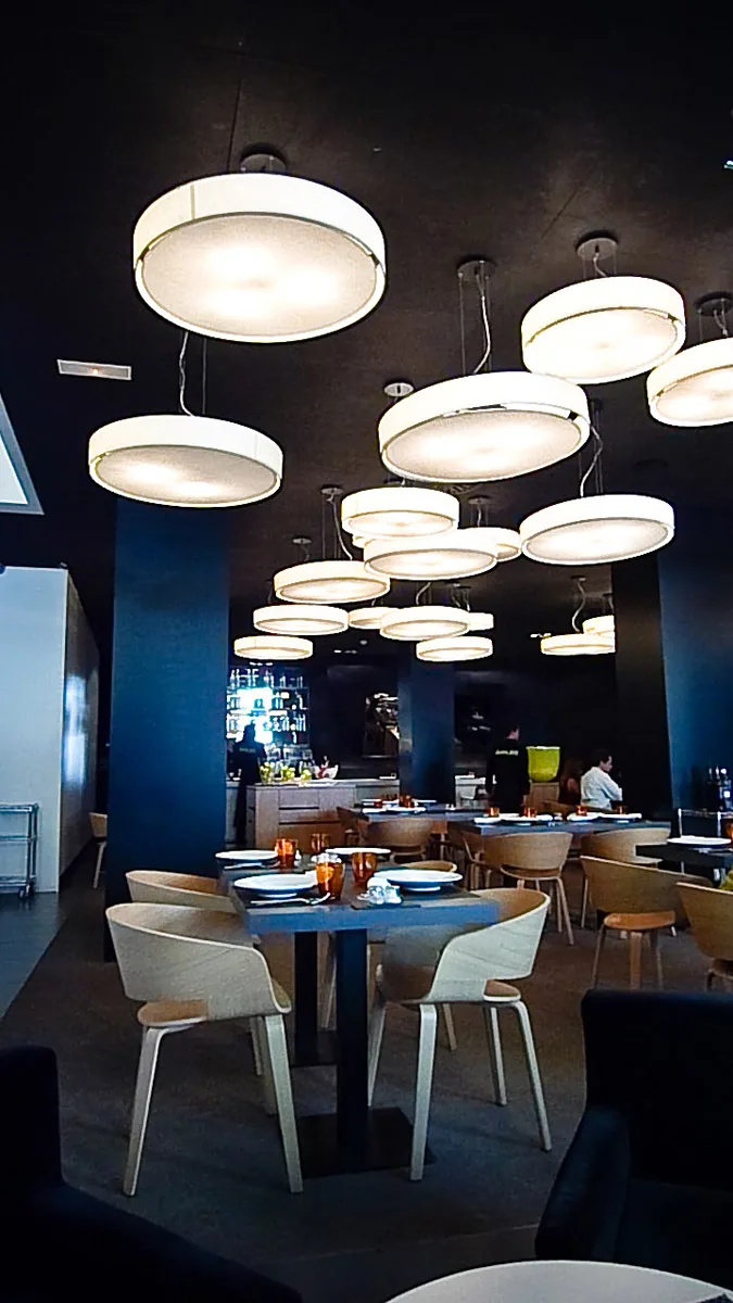 A hotel restaurant with blue walls and round pendant lights above the tables