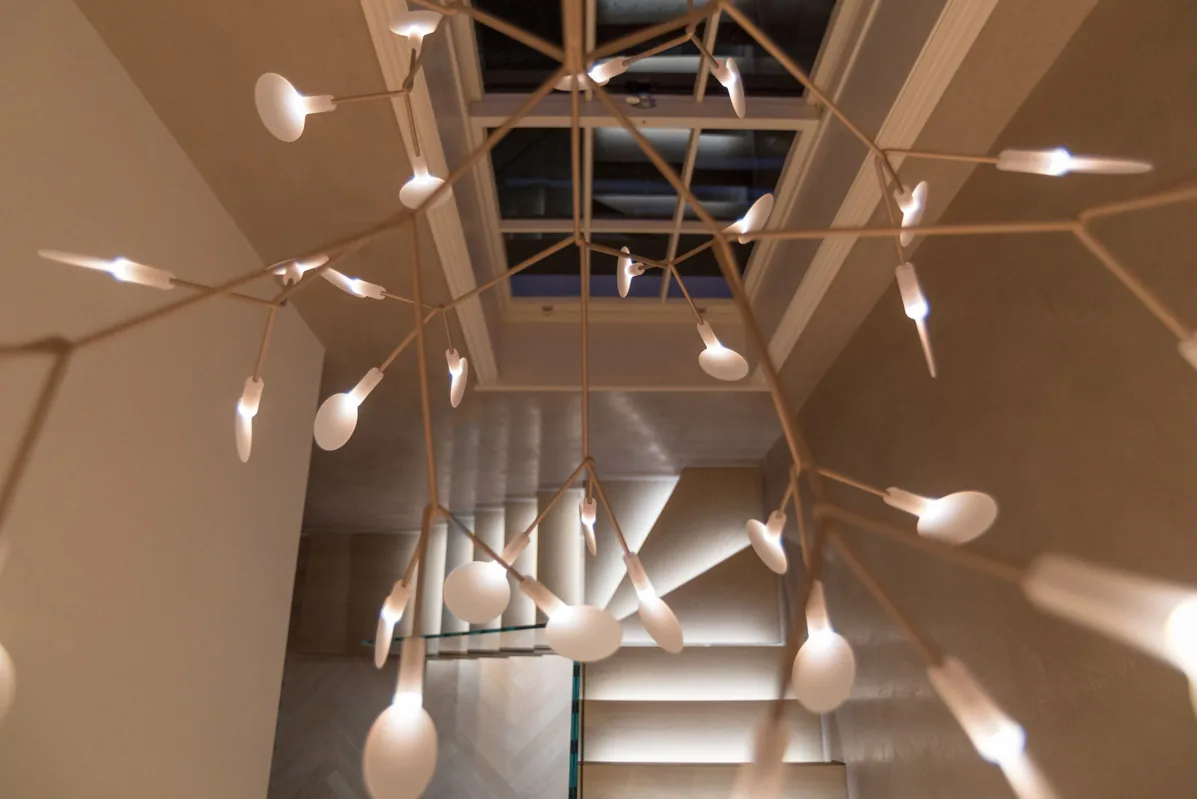 A cluster of glowing pendant lights hanging through a stairwell