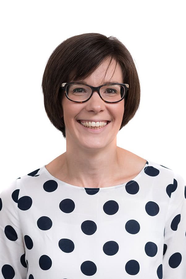 Smiling woman with glasses in professional corporate headshot.