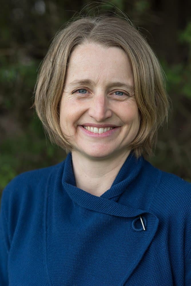 Portrait of a woman smiling outdoors, showcasing natural lighting and confident expression.