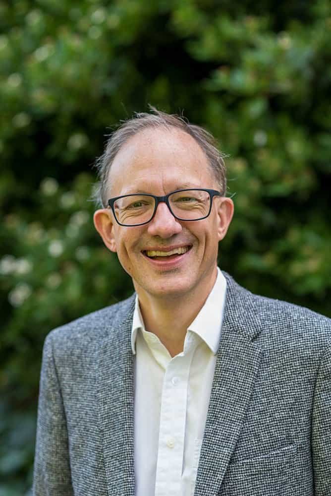 Professional portrait of a smiling man in a grey blazer for corporate photography.