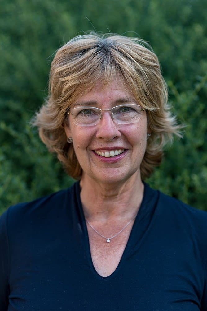 Portrait of a smiling woman with glasses, natural background, suitable for corporate headshots.